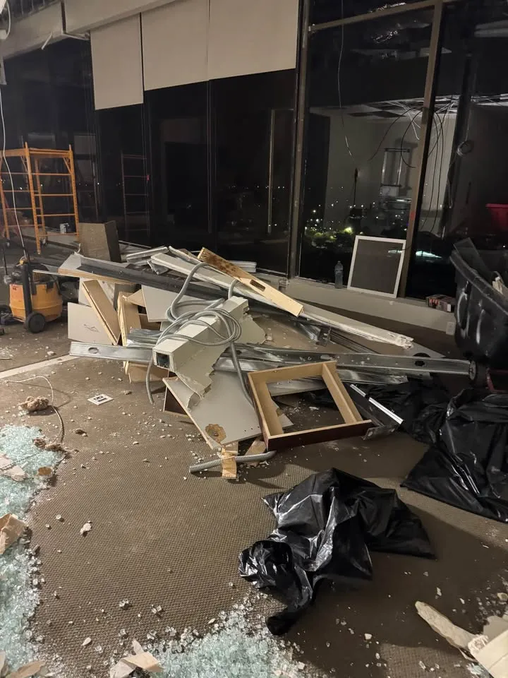 Commercial space mid strip-out with metal framing and debris piled on the floor
