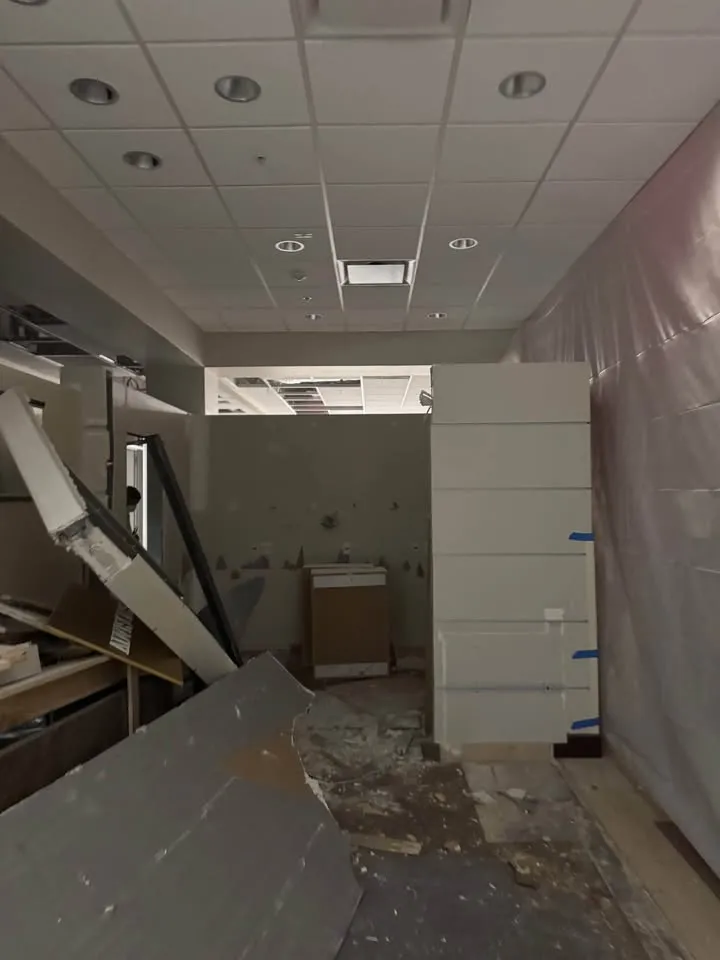 Office corridor with a partition wall and ceiling grid being taken down
