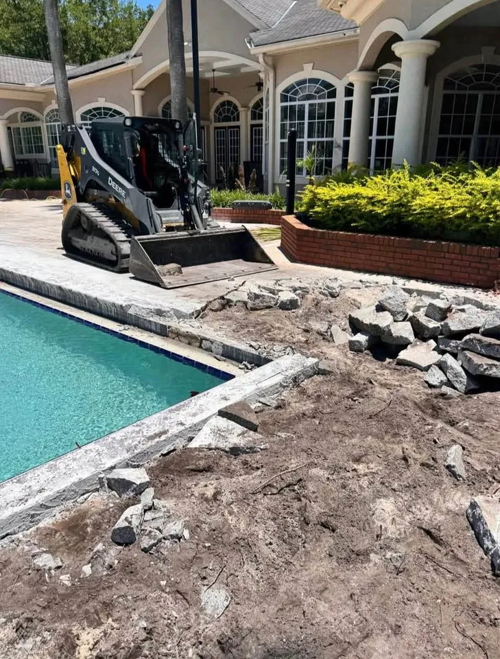 Compact track loader clearing the broken concrete surround of an outdoor pool