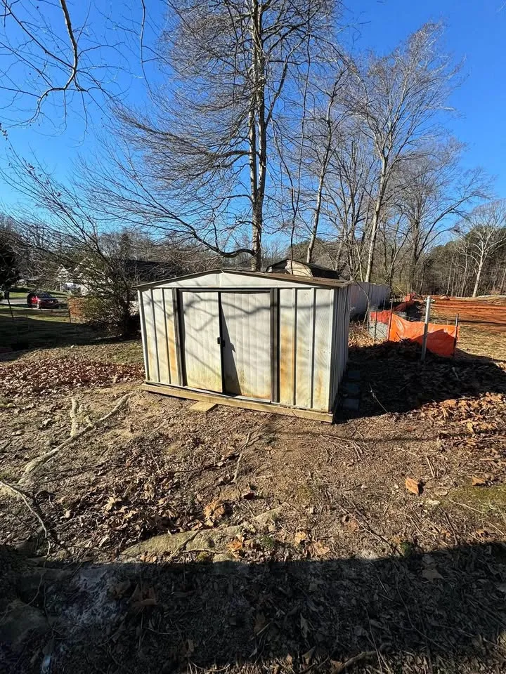 Small timber outbuilding with an open doorway, before removal