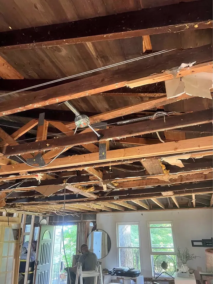 Ceiling opened to the joists and wiring above a stripped living room