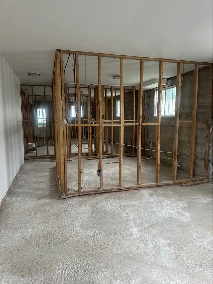 Interior wall stripped back to wood studs on a bare concrete floor