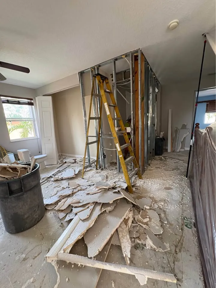Wall framing exposed and drywall pieces piled on the floor of a gutted room