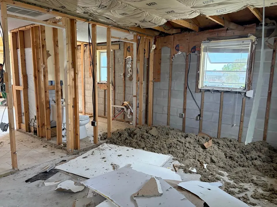 Room gutted to the studs and block wall with insulation piled on the floor