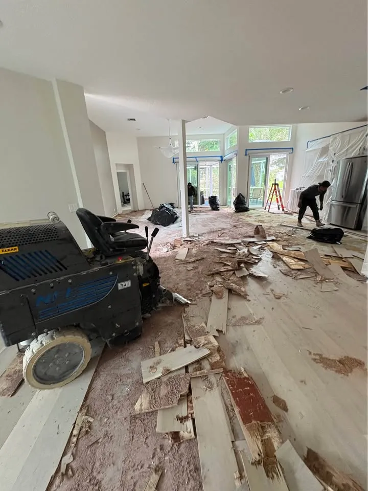 Ride-on floor scraper lifting old flooring across an open-plan main floor
