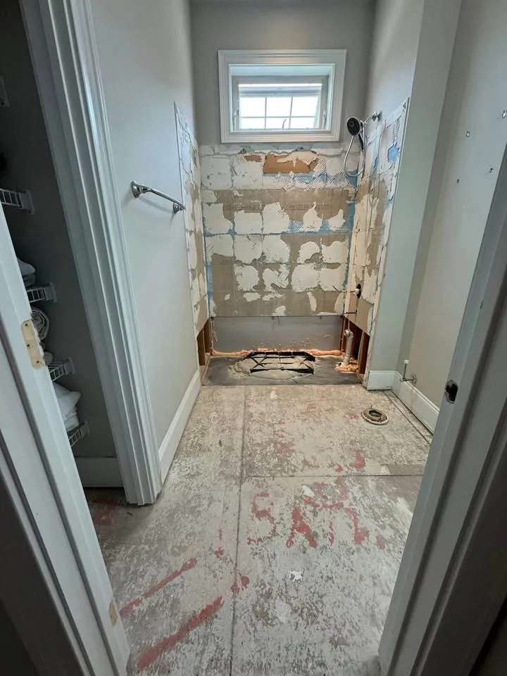 Shower stripped to the backer board with tile adhesive marks and the floor tile removed