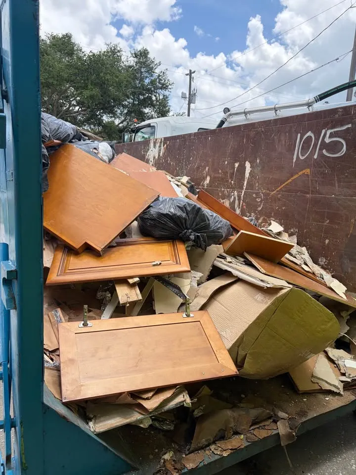 Roll-off bin filled with cabinet doors and cardboard from a kitchen tear-out