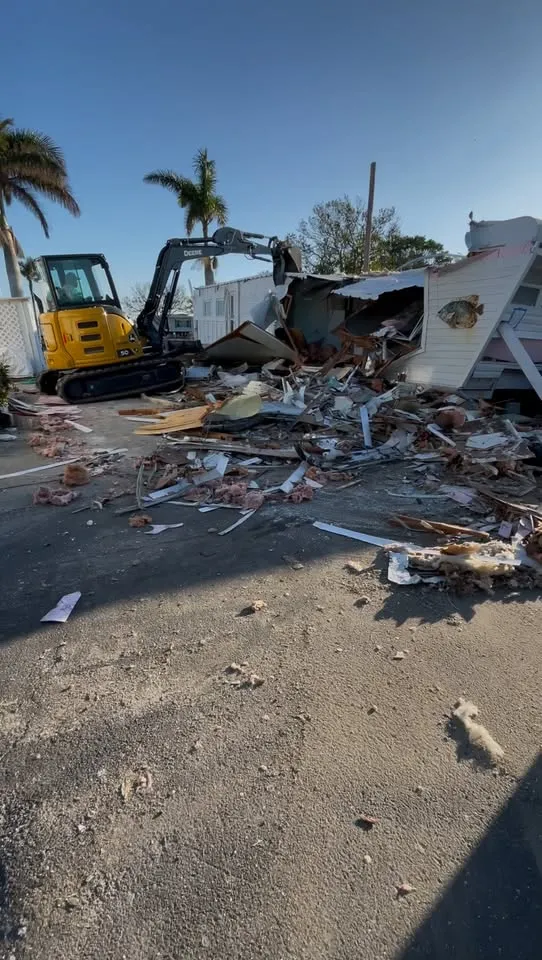 Excavator working through the remains of a single-storey house on a sunny lot