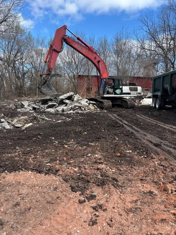 Red excavator stacking broken concrete and masonry after a building has been brought down
